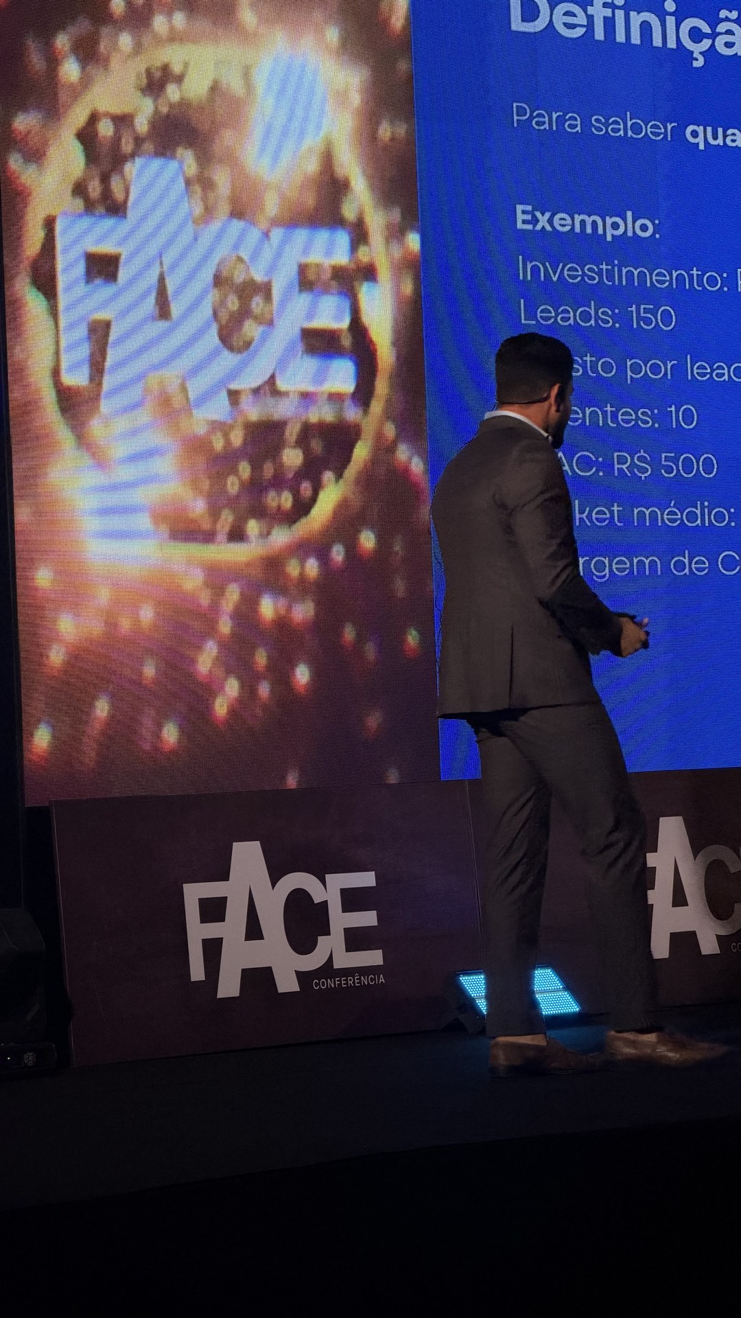 Vitor Rehbein no palco diante do telão iluminado
